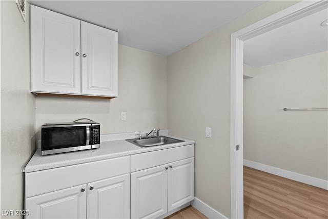 interior space with baseboards, light wood-type flooring, and a sink