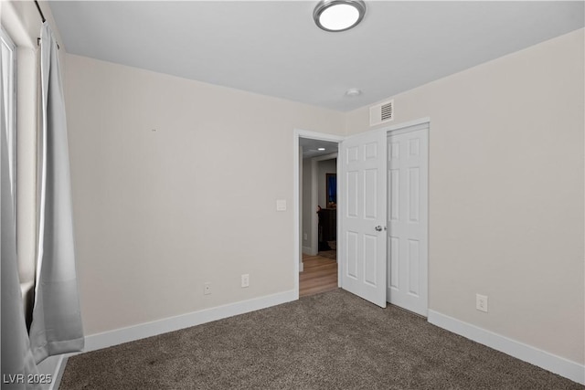 unfurnished bedroom featuring carpet, baseboards, a closet, and visible vents