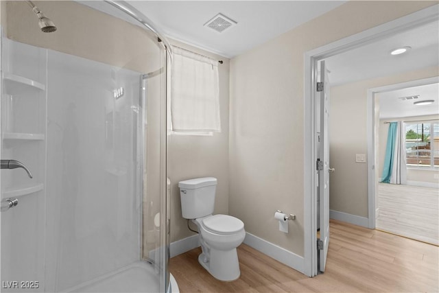 bathroom featuring toilet, baseboards, visible vents, a shower stall, and wood finished floors
