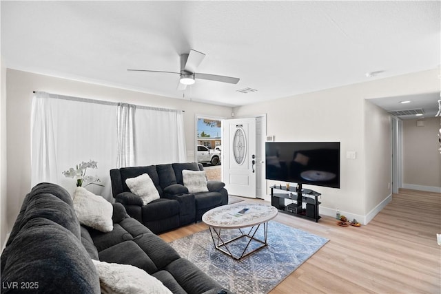 living area with light wood finished floors, visible vents, baseboards, and ceiling fan