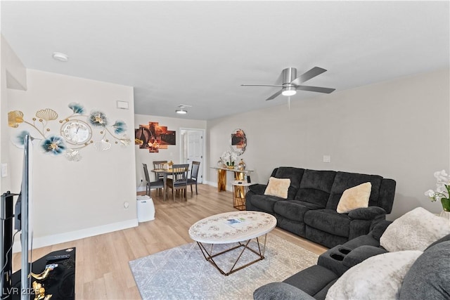 living area featuring a ceiling fan, baseboards, and light wood-style flooring