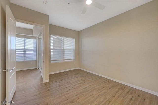 empty room with baseboards, ceiling fan, and light wood-type flooring