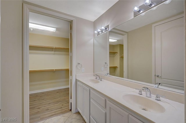 bathroom featuring tile patterned floors, double vanity, a walk in closet, and a sink