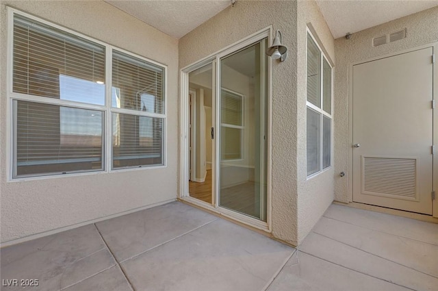 doorway to property with a patio area, stucco siding, and visible vents