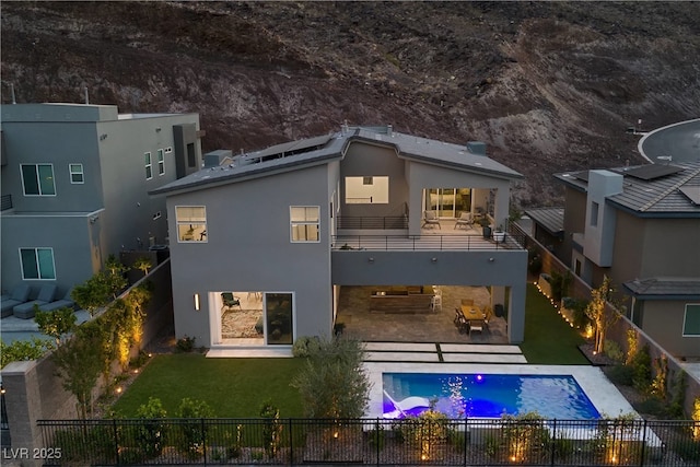 back of house with a patio area, a balcony, stucco siding, a fenced backyard, and a lawn