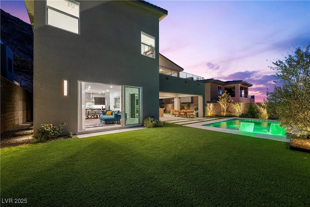 back of property featuring a patio, stucco siding, and a lawn