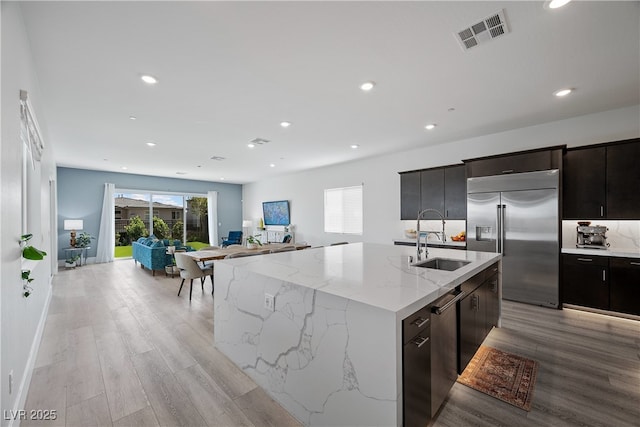 kitchen with visible vents, a sink, open floor plan, stainless steel appliances, and light wood-type flooring