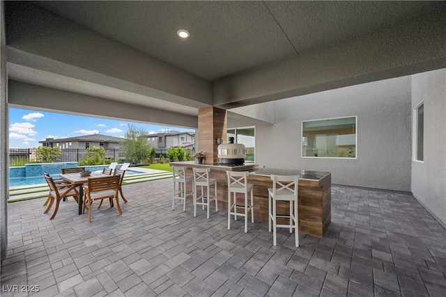 view of patio with fence, a fenced in pool, grilling area, and outdoor dry bar