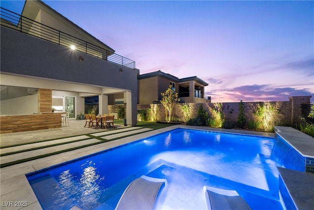 pool at dusk featuring a patio area, a fenced in pool, and a fenced backyard