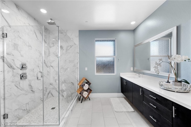 full bathroom featuring a marble finish shower, baseboards, vanity, and tile patterned flooring