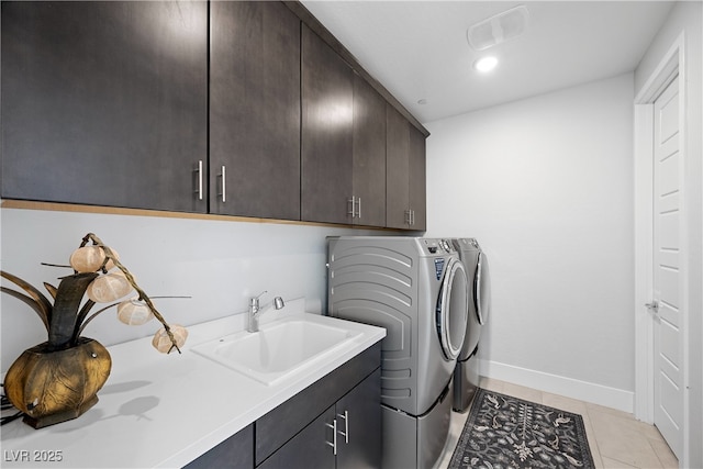 clothes washing area with a sink, cabinet space, washer and dryer, light tile patterned floors, and baseboards