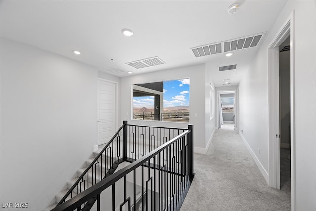 hallway featuring light carpet, an upstairs landing, and visible vents