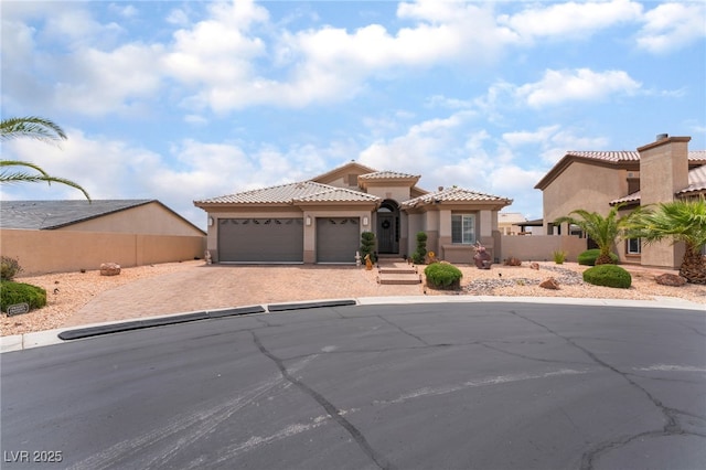 mediterranean / spanish-style house with driveway, a tiled roof, fence, an attached garage, and stucco siding