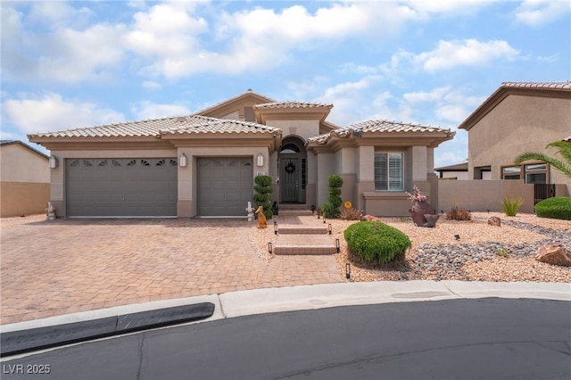 mediterranean / spanish-style home with fence, decorative driveway, a garage, stucco siding, and a tile roof