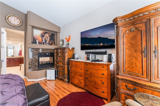 living area featuring light wood-style floors, vaulted ceiling, and a multi sided fireplace