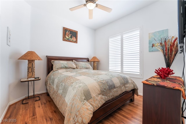 bedroom with baseboards, multiple windows, ceiling fan, and wood finished floors