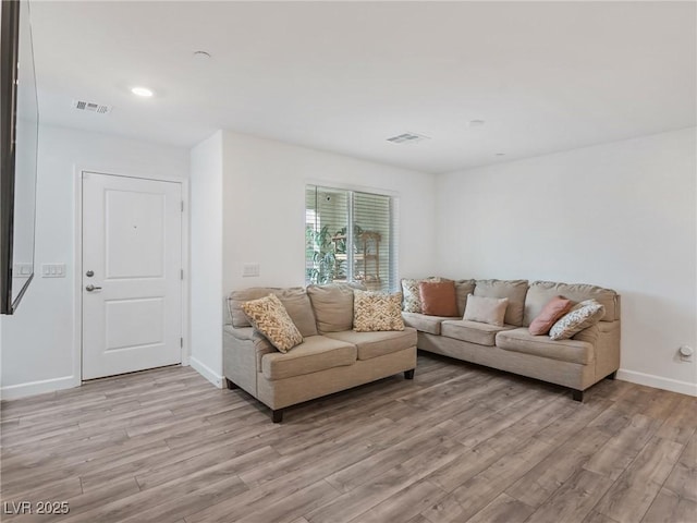 living room featuring baseboards, light wood-style floors, and visible vents