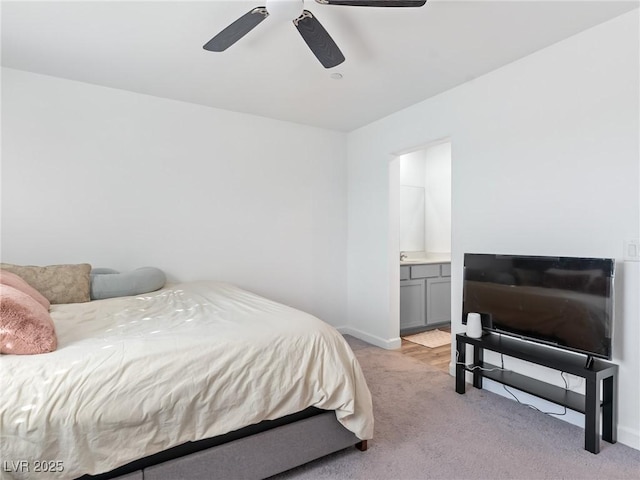 bedroom with baseboards, ensuite bathroom, ceiling fan, and light colored carpet