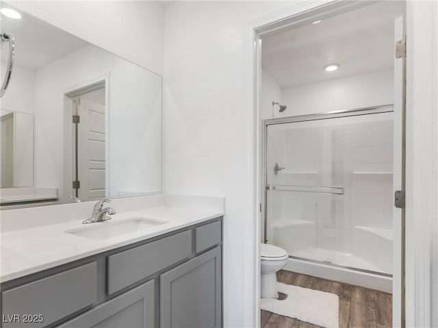 full bathroom featuring a shower stall, vanity, toilet, and wood finished floors