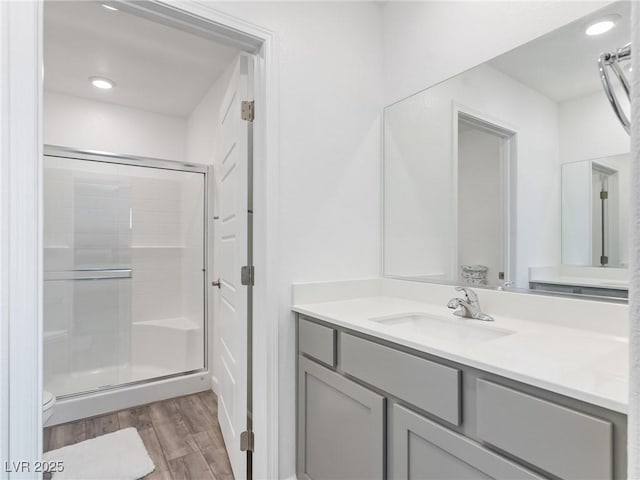 bathroom featuring vanity, wood finished floors, a shower stall, and toilet