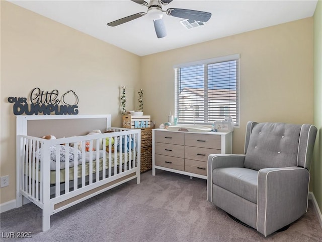carpeted bedroom featuring a nursery area, visible vents, and ceiling fan