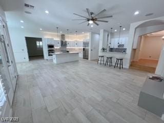 living room featuring a ceiling fan, recessed lighting, and arched walkways