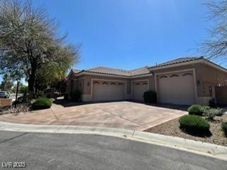 view of front of home with driveway, stucco siding, a tiled roof, and an attached garage