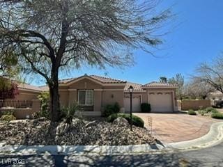 view of front facade with an attached garage, a tiled roof, stucco siding, and driveway