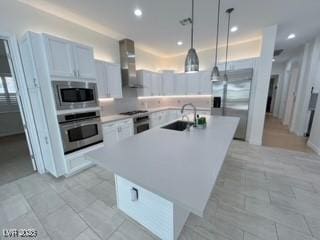 kitchen featuring appliances with stainless steel finishes, recessed lighting, a sink, wall chimney exhaust hood, and an island with sink