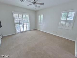 spare room featuring baseboards, visible vents, ceiling fan, and plenty of natural light