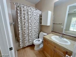 bathroom featuring toilet, vanity, shower / bath combo with shower curtain, and wood finished floors