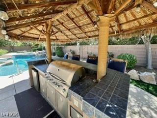 view of patio / terrace featuring a fenced backyard, an outdoor kitchen, and a fenced in pool