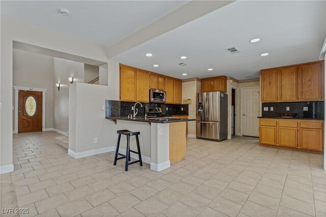 1287 Dove Tree Ct, Henderson, NV 89014 - kitchen featuring a peninsula, a kitchen breakfast bar, visible vents, decorative backsplash, and appliances with stainless steel finishes