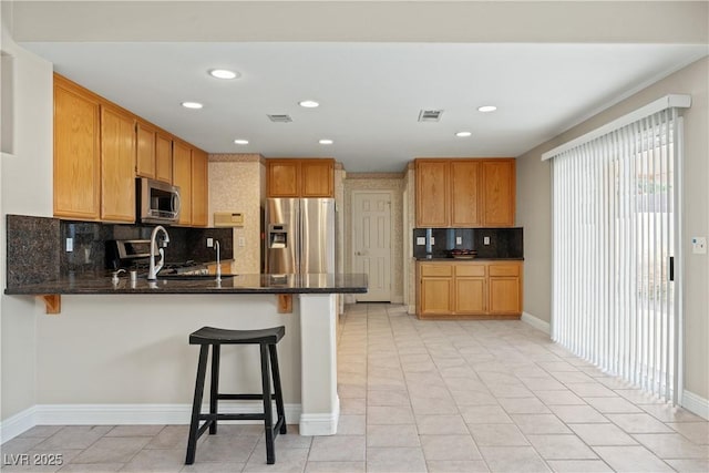 1287 Dove Tree Ct, Henderson, NV 89014 - kitchen with recessed lighting, visible vents, a peninsula, backsplash, and appliances with stainless steel finishes