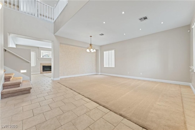 1287 Dove Tree Ct, Henderson, NV 89014 - empty room featuring a fireplace, stairway, visible vents, light colored carpet, and a chandelier