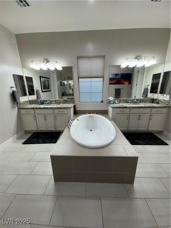 full bathroom featuring tile patterned floors, a garden tub, baseboards, and two vanities
