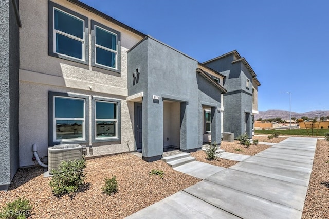 modern home featuring cooling unit, a mountain view, and stucco siding