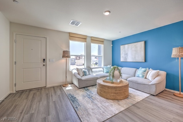 living room with baseboards, visible vents, and wood finished floors