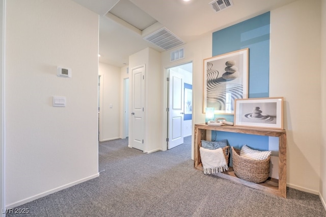 hall with attic access, visible vents, and carpet floors
