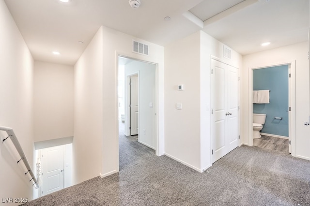 hallway featuring carpet flooring, visible vents, and baseboards