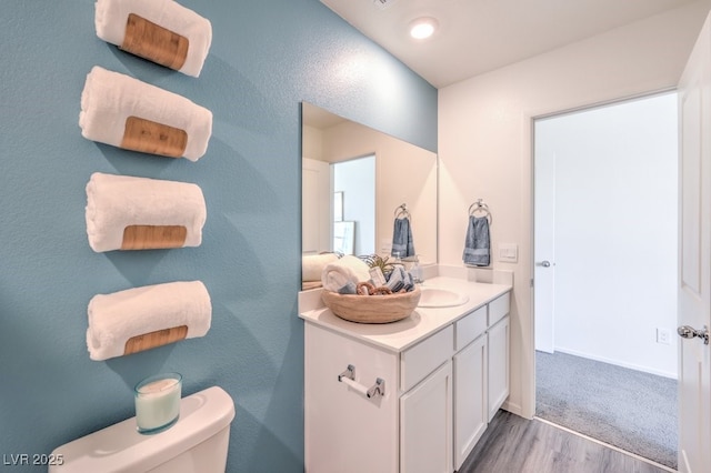 bathroom with toilet, baseboards, vanity, and wood finished floors