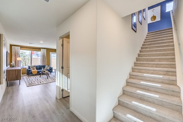stairs with baseboards, visible vents, and wood finished floors