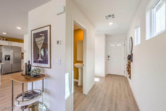 corridor with light wood finished floors, visible vents, baseboards, and recessed lighting