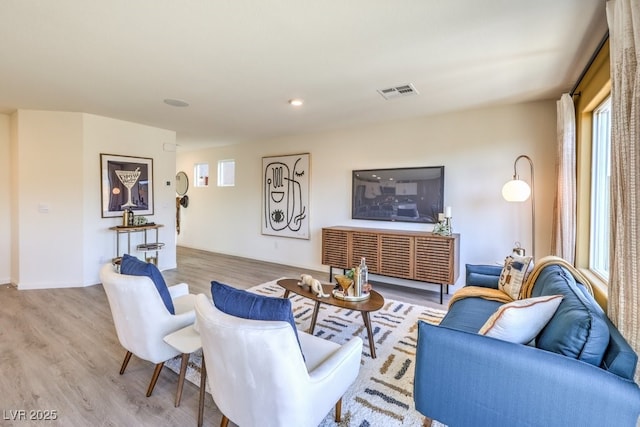 living room with a wealth of natural light, visible vents, and wood finished floors