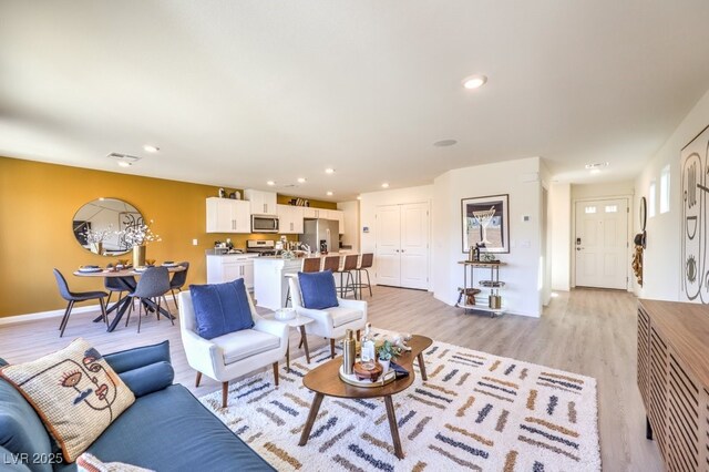 living room with recessed lighting, light wood finished floors, and visible vents