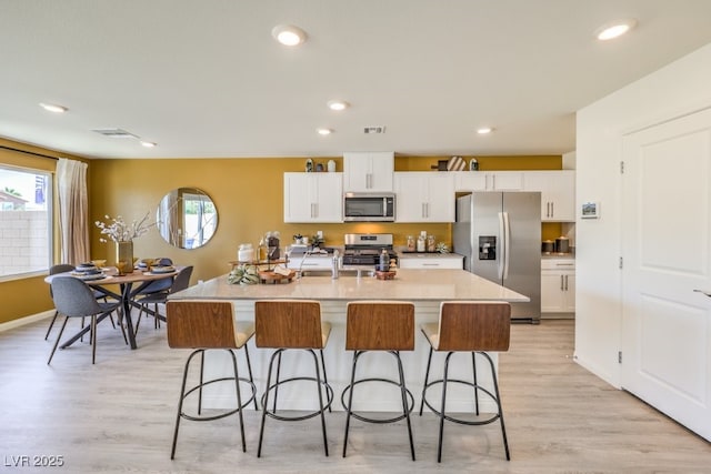 kitchen with a breakfast bar area, stainless steel appliances, and white cabinetry