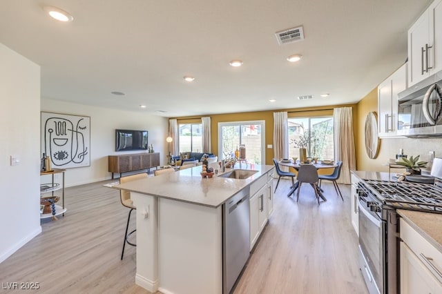 kitchen with appliances with stainless steel finishes, plenty of natural light, visible vents, a sink, and light wood-type flooring