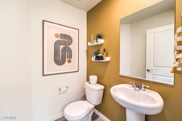 bathroom with toilet, baseboards, and a sink