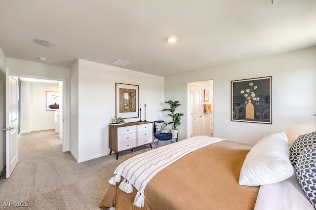 carpeted bedroom featuring ensuite bath, baseboards, and visible vents