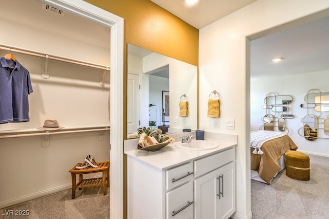 ensuite bathroom with vanity, a walk in closet, ensuite bathroom, and visible vents